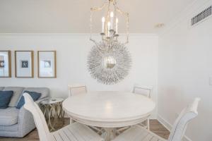 a dining room with a white table and a chandelier at Phoenix VI 6906 in Orange Beach