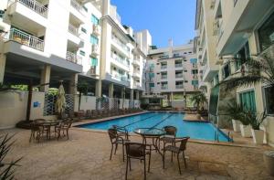 a swimming pool with tables and chairs next to a building at Bombinhas summer bech in Bombinhas