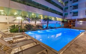 a large pool in a hotel with chairs around it at Bombinhas summer bech in Bombinhas