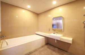 a bathroom with a tub and a sink and a mirror at 아셈호텔 in Taech'on