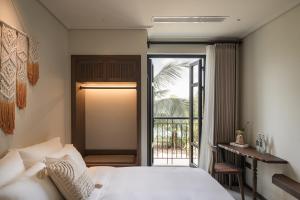 a bedroom with a bed and a door to a balcony at Su Casa Phu Quoc Long Beach in Phú Quốc +100 photos