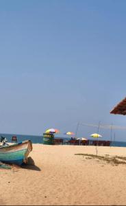 a boat sitting on a beach with umbrellas at Dolphin beach resort in Varkala