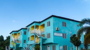 a blue building with white balconies and a palm tree at Lamblion Holiday Apartment in Freemans