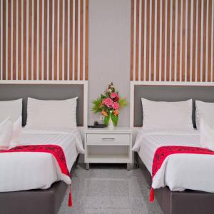 a bedroom with two beds and a vase of flowers at โกลเด้นแลนด์รีสอร์ท in Ban Dan Kwian
