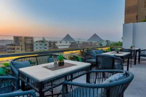 a group of tables and chairs on a balcony with a view at TAJ Suites Pyramids View Hotel in Cairo