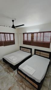 two beds in a room with a ceiling fan at D3 Homes in Jāmb