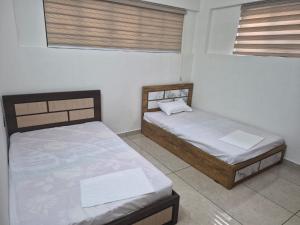 two beds in a room with two windows at D3 Homes in Jāmb