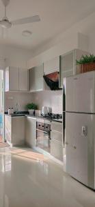 a kitchen with white cabinets and a stainless steel refrigerator at Nala Host - 2BR Garden Home in Hulhumale
