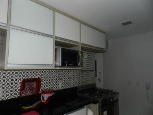 cocina con armarios blancos y microondas en Apartamento Vista Mar Rio Vermelho en Salvador