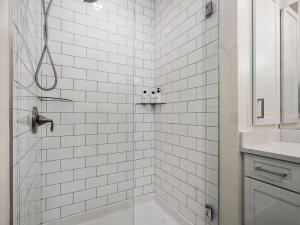 a white tiled bathroom with a shower and a sink at Cozy Capri Condo: Charming 1BR 1BA Downtown! in Traverse City +21 photos