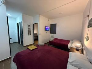 a hotel room with two beds and a tv at Suites Apodaca in Monterrey