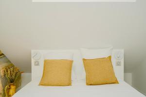 a white bed with two yellow pillows on it at Maison Soleil Levant in Vernon +17 photos