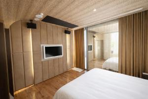 a bedroom with a bed and a tv on the wall at Holly Wood Motel in Pitou