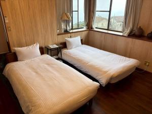 two beds sitting in a room with a window at Atami Ocean & Star Cottage in Atami