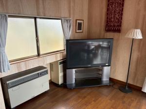 a living room with a flat screen tv and two windows at Atami Ocean & Star Cottage in Atami