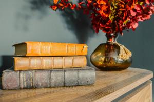 a stack of books and a vase with flowers on a table at Maison Kolsaas in Vernon