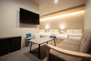 a hotel room with two beds and a flat screen tv at Fam Hotel Imaizumi in Fukuoka