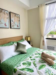 a bedroom with a green and white bed with a window at Mactan Plains Residences in Mactan