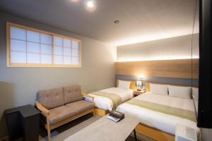 a hotel room with two beds and a chair at Fam Hotel Imaizumi in Fukuoka