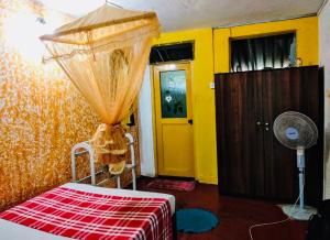 a room with a bed and a yellow door and a fan at Pick Me Village in Dambulla