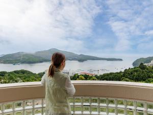 a woman standing on a balcony looking out at the water at Toba Ocean Resort All-Inclusive Hotel in Toba