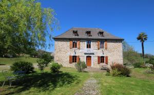 an old stone house in a yard with a palm tree at Maison poumarou in Sainte-Colome