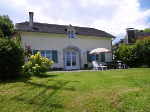 a white house with a chair and an umbrella at Peyre in Aramits