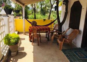 a patio with a table and chairs and a yellow wall at Pick Me Village in Dambulla