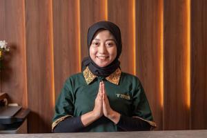 a woman in a green dress and hijab praying at Trifena Residence in Kalibanteng-lor