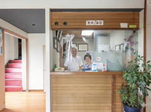 a woman standing behind a counter in a restaurant at Tabist Futaba Ryokan Tatsuno in Tatsuno