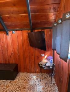 a room with wooden walls and a tv and a table at Cabaña Joy-C Colibri 1 in El Copey