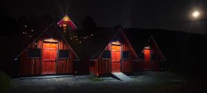 a row of wooden houses with red doors at night at Cabaña Joy-C Colibri 1 in El Copey