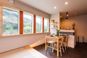 a kitchen with a table and chairs and windows at MEIBI Hakone Yumoto in Hakone