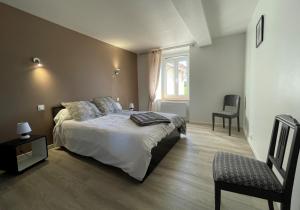 a bedroom with a bed and a chair and a window at Gite du coos in Audaux