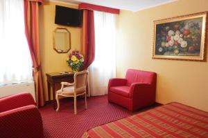 a hotel room with a red chair and a desk at Hotel Città Di Milano in Venice