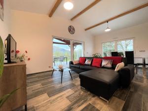 a living room with a black couch and red pillows at Eki-begia in Ainhice-Mongelos