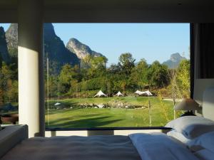 ein Schlafzimmer mit Blick auf einen Golfplatz durch ein Fenster in der Unterkunft YINGMAN HOTEL in Yangshuo