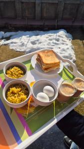 a table with a sandwich and scrambled eggs and food at Cliffside cottage in Tangmarg
