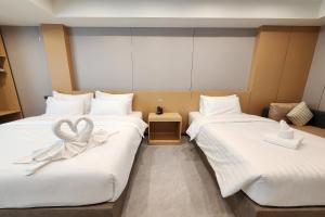 two beds with white sheets with a ribbon on them at VELIN Pattaya Hotel in Pattaya