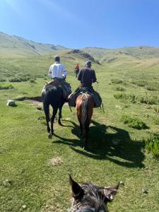 a group of people riding horses on a field at Dastans Homestay, Bed and Breakfast & Horse riding in Kyzart +63 photos