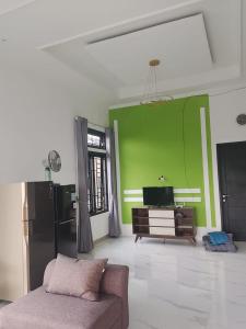 a living room with a couch and a green wall at Mroom Villa Cipanas in Pacet