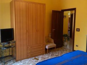 sypialnia z dużą drewnianą szafką i telewizorem w obiekcie Happy House Wifi Free Bici Free w mieście Avola