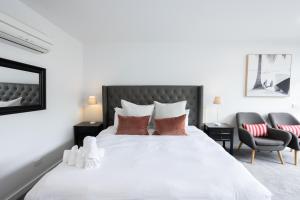a bedroom with a large white bed with two chairs at Bay View Sunrise in Lorne