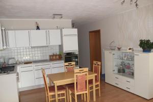 a kitchen with white cabinets and a table and chairs at Luba in Hillesheim