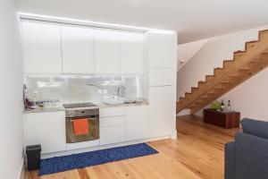 una cocina con armarios blancos y una escalera en Apartamento City Center, en Oporto