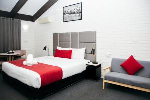 a bedroom with a large bed and a chair at All Travellers Motor Inn in Coonabarabran