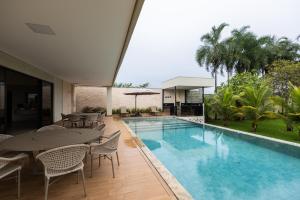 a swimming pool with tables and chairs next to a building at Espaço JF in Aparecida de Goiânia +17 photos