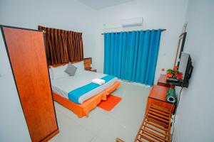 a bedroom with a bed and a blue curtain at Meth Suites in Epamulla