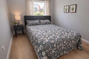 a bedroom with a bed with a floral bedspread and a window at Jefferson Sr - 20 mins to Manhattan, NYC in West New York