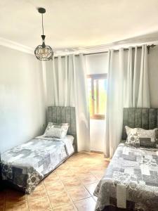 a bedroom with two beds and a chandelier at Résidence Costa Cabo in Martil +11 photos